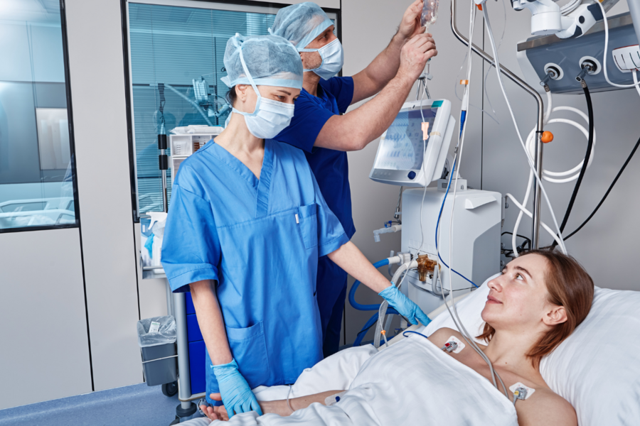 Patient in a hospital bed is comforted by a medical practitioner