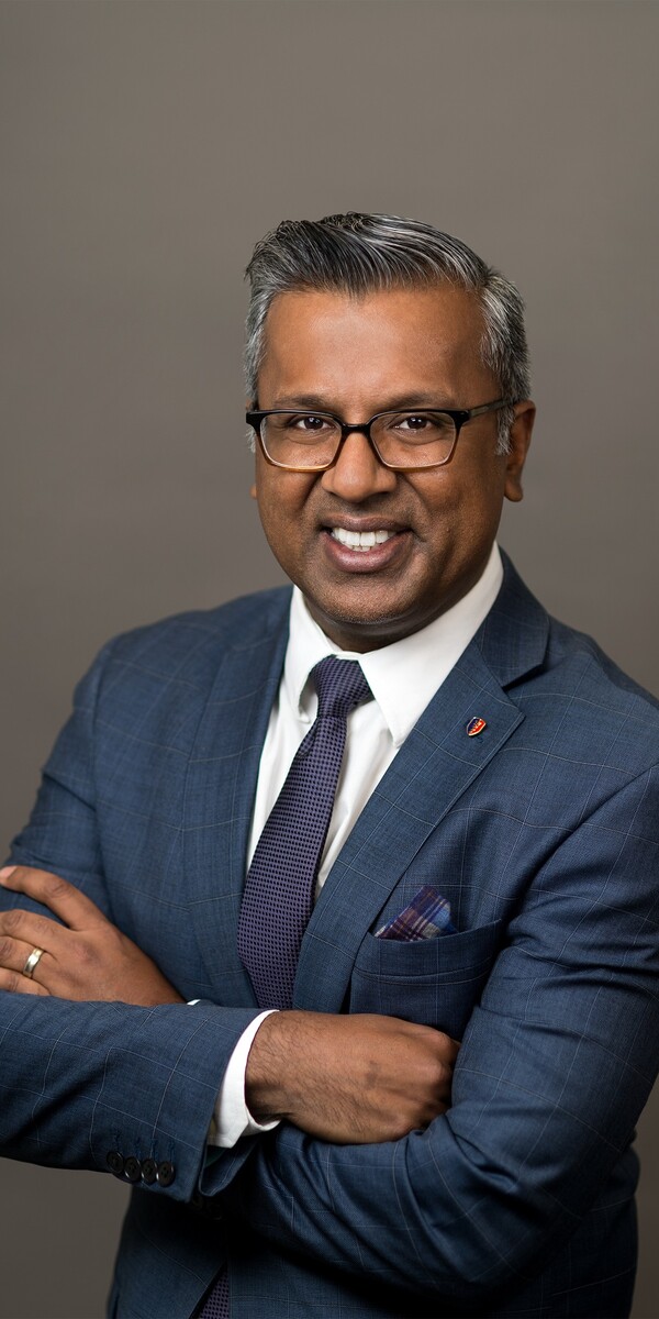 Dr. Viren Naik against a grey background