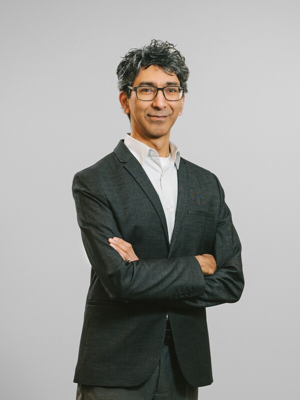 Dr. Vaibhav Kamble, arms folded, against a grey background