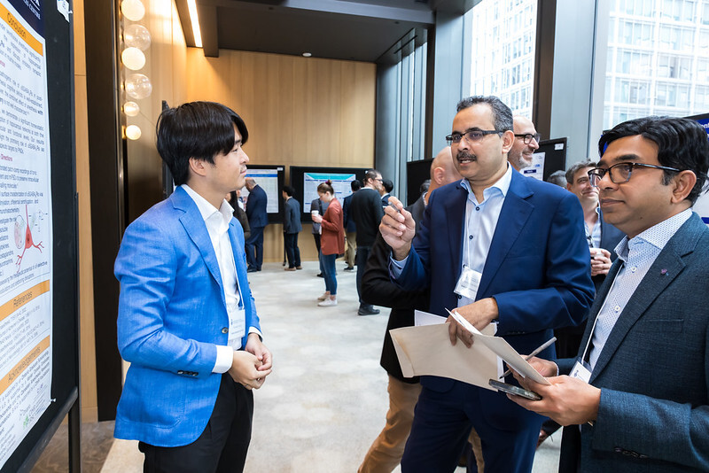 Three individuals discussing a poster.