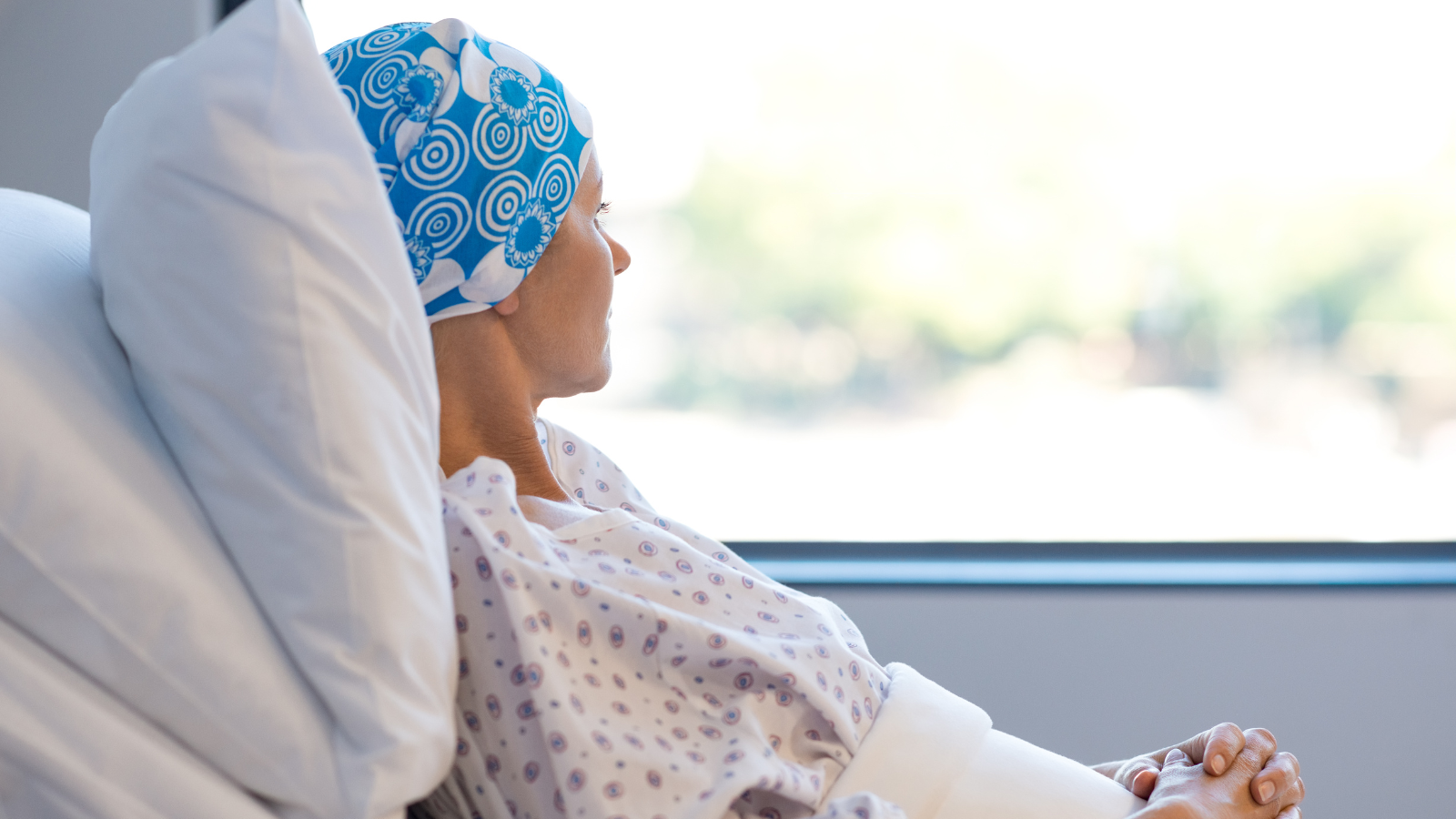 Patient lays in a hospital bed staring out of a window