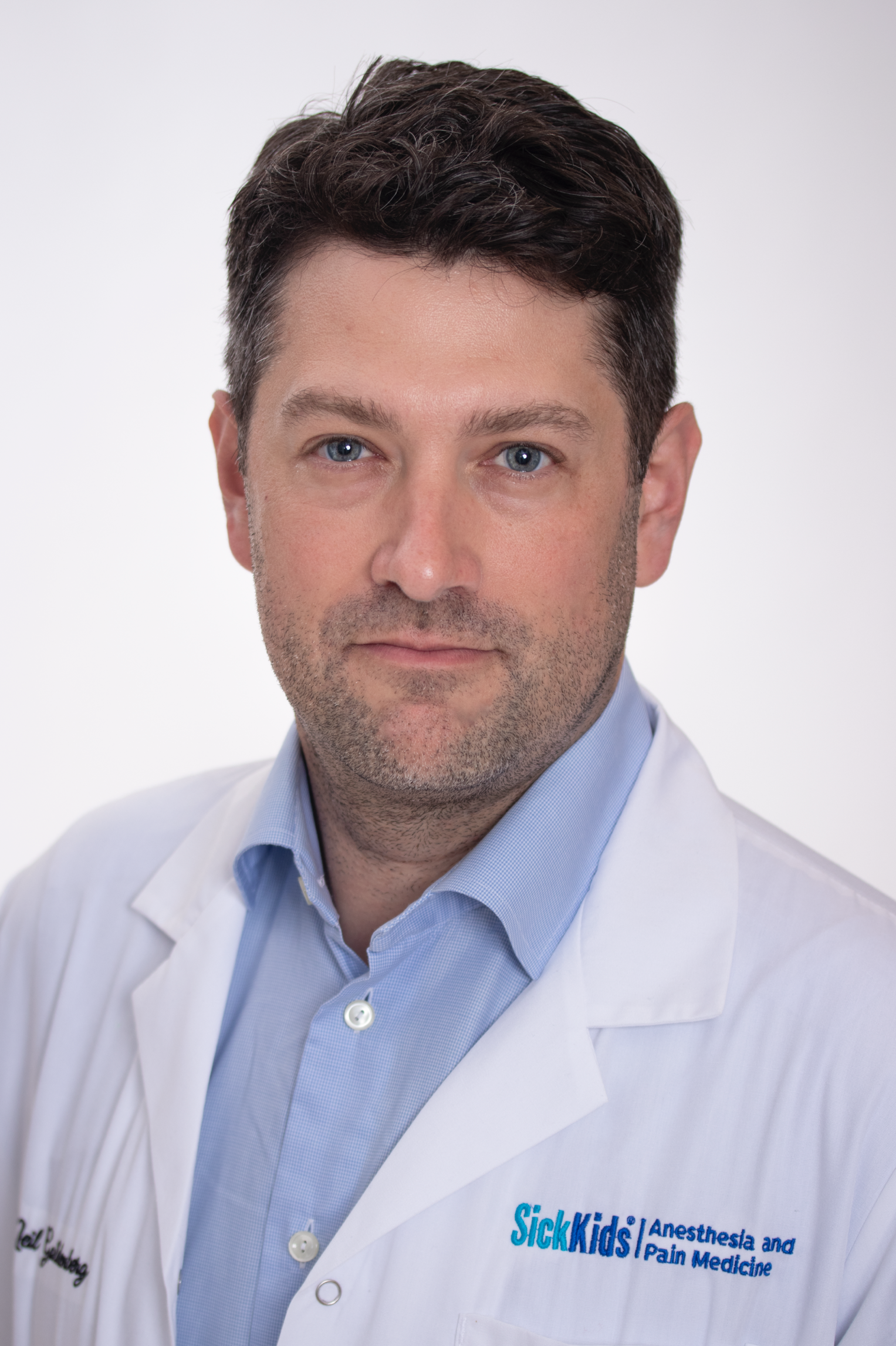 Dr. Goldenberg wears a white SickKids branded labcoat against a white background. 